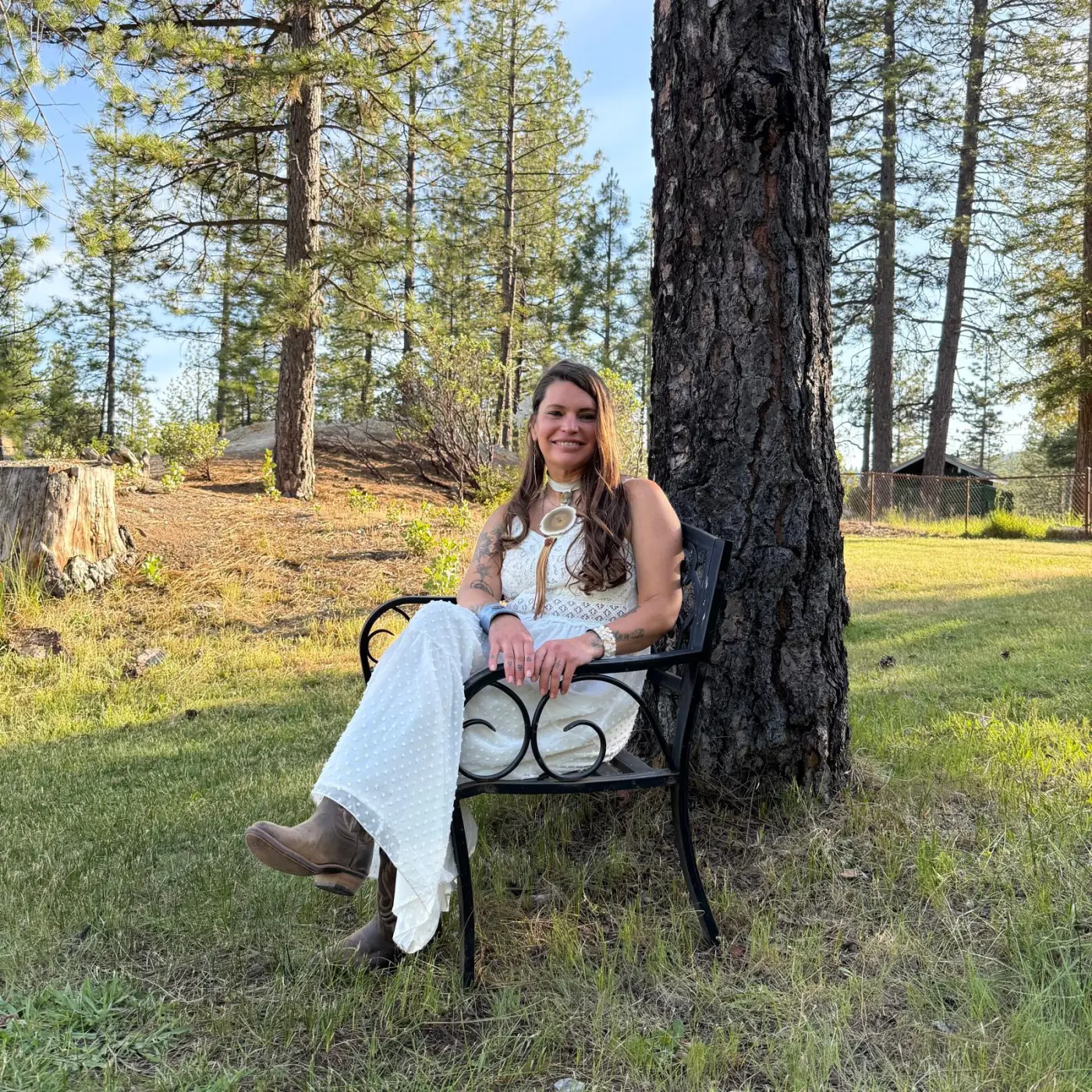 Athena Rose seated in a sunlit pine grove